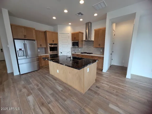 a large kitchen with stainless steel appliances a refrigerator a stove a sink dishwasher and a oven with wooden floors