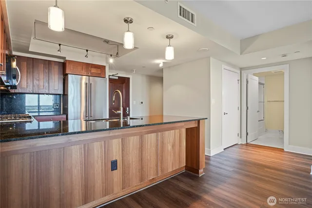 a kitchen with stainless steel appliances a refrigerator and wooden floor