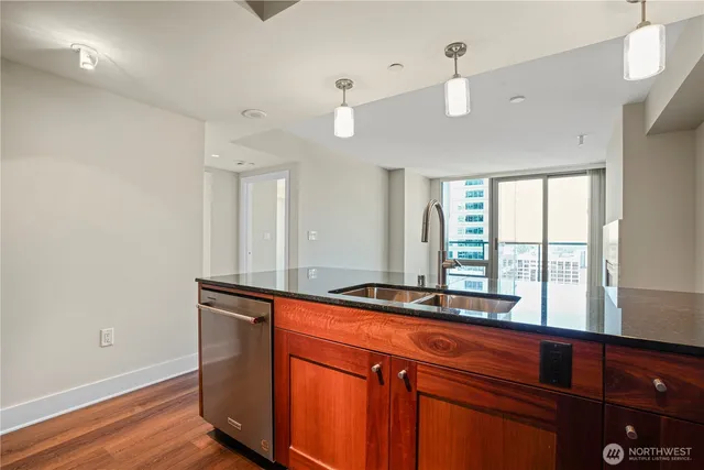 a kitchen with stainless steel appliances granite countertop a sink and a wooden floor