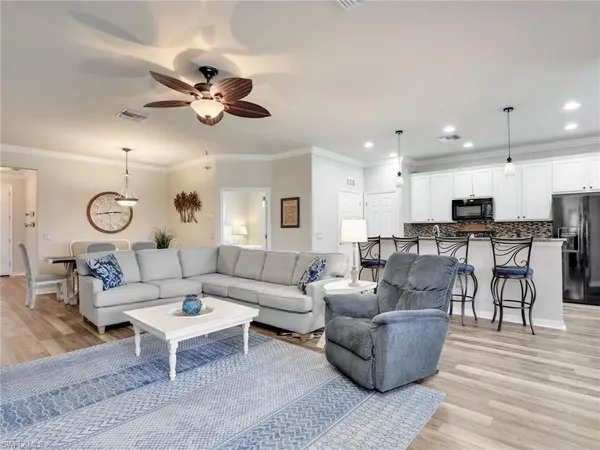 a living room with furniture kitchen view and a chandelier