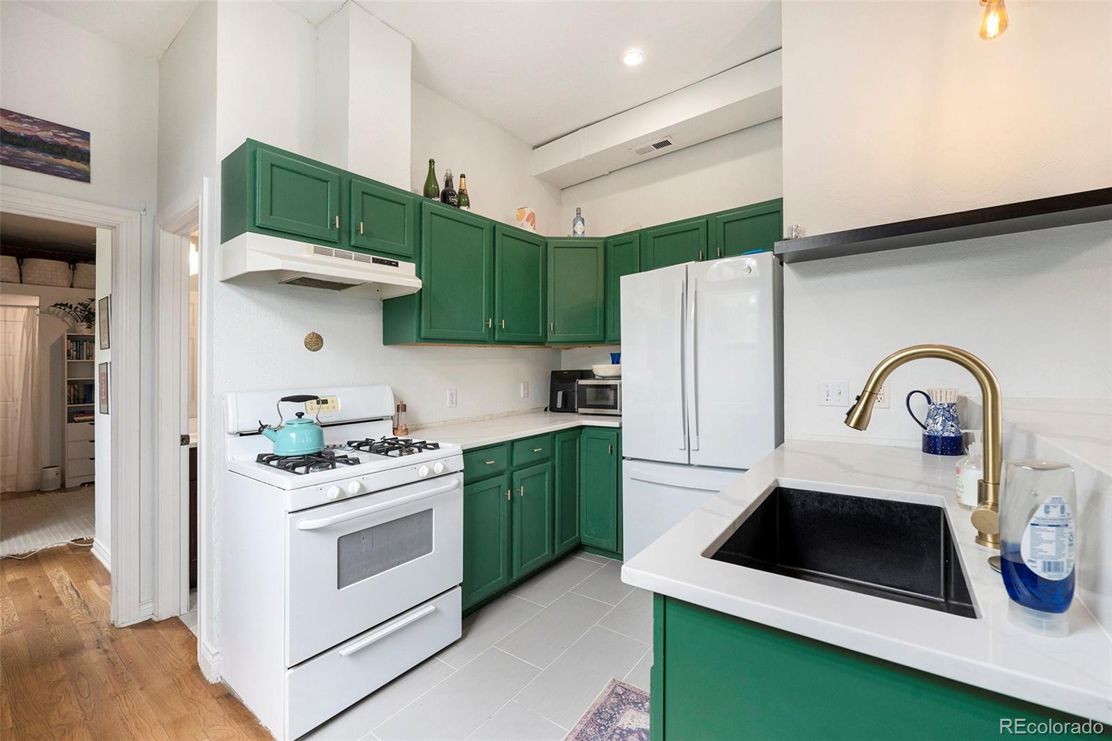 474 Inca Street Denver, CO 80204 - Photo 5 of 15 a kitchen with stainless steel appliances a stove a sink and a refrigerator with wooden floor