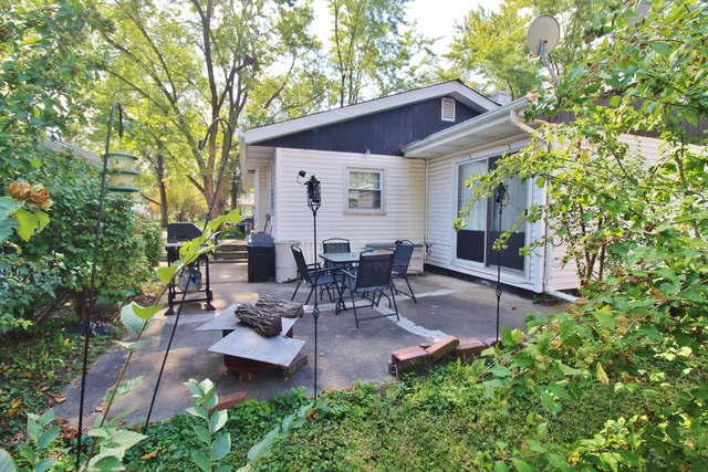 a view of a patio with table and chairs potted plants and large tree