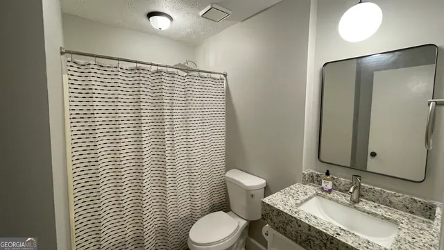 a bathroom with a granite countertop toilet sink and mirror