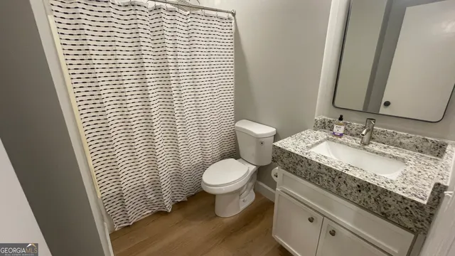 a bathroom with a granite countertop toilet a sink and a mirror