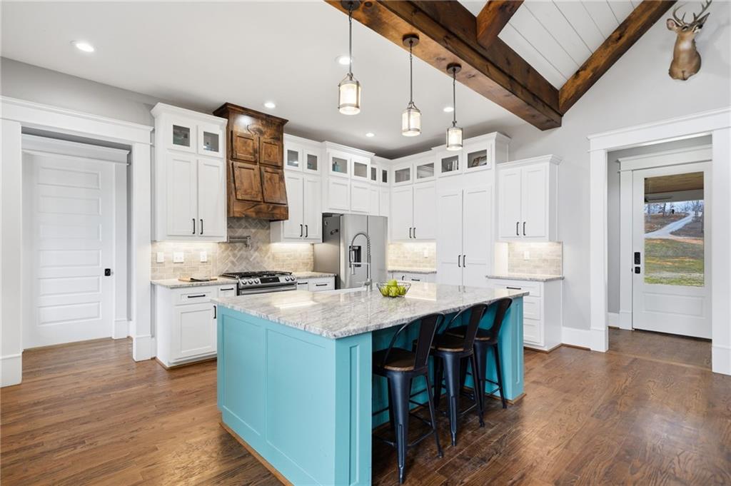 1100 Soap Creek Road Ball Ground, GA 30107 - Photo 26 of 107 a kitchen with stainless steel appliances granite countertop a stove a refrigerator a sink dishwasher and a dining table with wooden floor