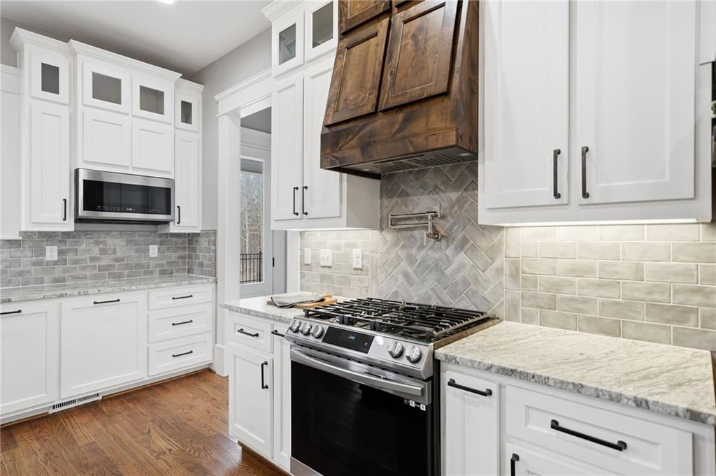 1100 Soap Creek Road Ball Ground, GA 30107 - Photo 28 of 107 a kitchen with stainless steel appliances granite countertop white cabinets a stove top oven with wooden floor