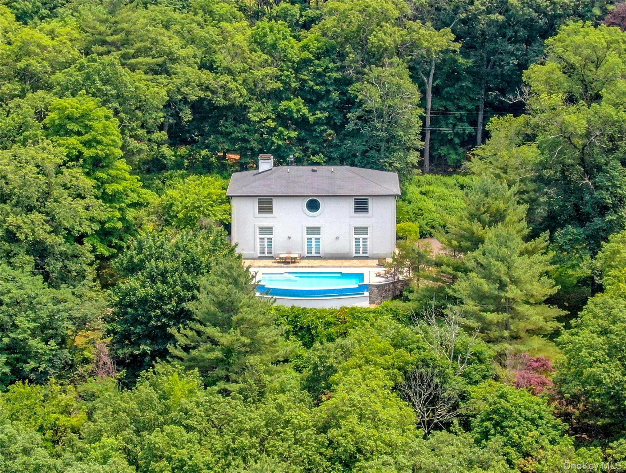 Aerial view of property and surrounding area featuring a heavily wooded area and a pool