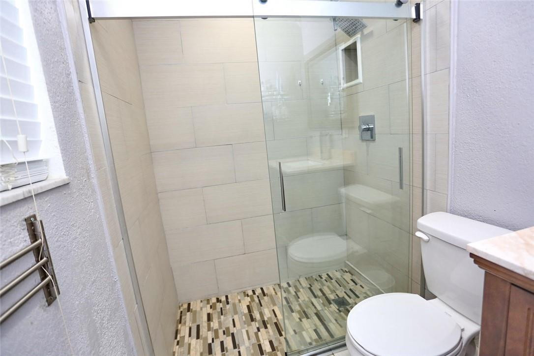6960 Southwest 1st Street Margate, FL 33068 - Photo 26 of 36 a white toilet sitting next to a bathroom sink and a shower