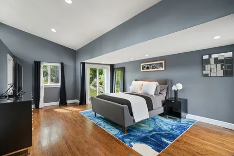 a spacious bedroom with a bed and wooden floor