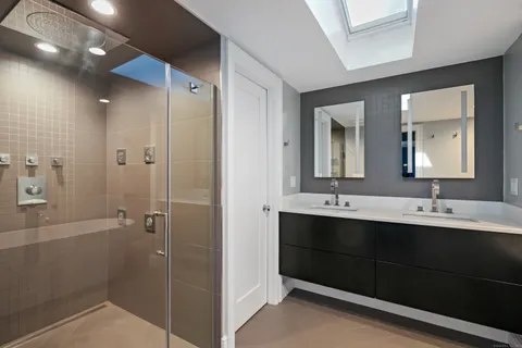 a bathroom with a double vanity sink mirror and shower