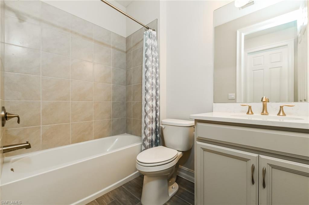 1059 Enbrook Loop Naples, FL 34114 - Photo 12 of 19 Full bathroom featuring vanity, wood tiled floors, and shower / tub combo