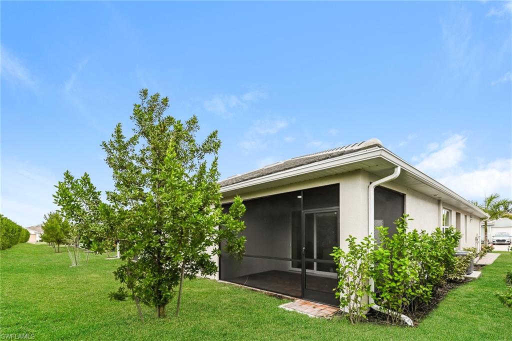 1059 Enbrook Loop Naples, FL 34114 - Photo 13 of 19 Rear view of property with a lawn, a sunroom, and stucco siding