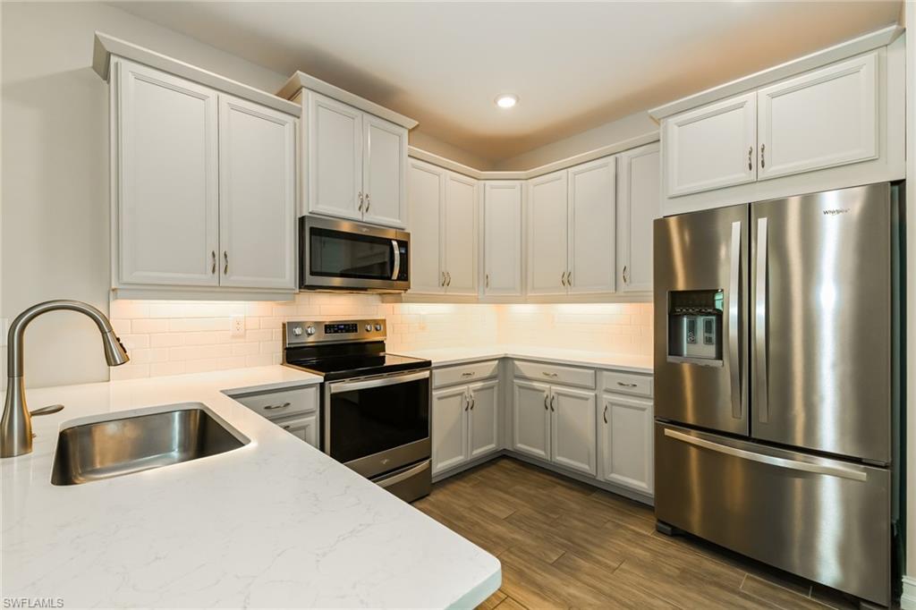 1059 Enbrook Loop Naples, FL 34114 - Photo 2 of 19 Kitchen with stainless steel appliances, backsplash, dark wood-style flooring, recessed lighting, and white cabinetry