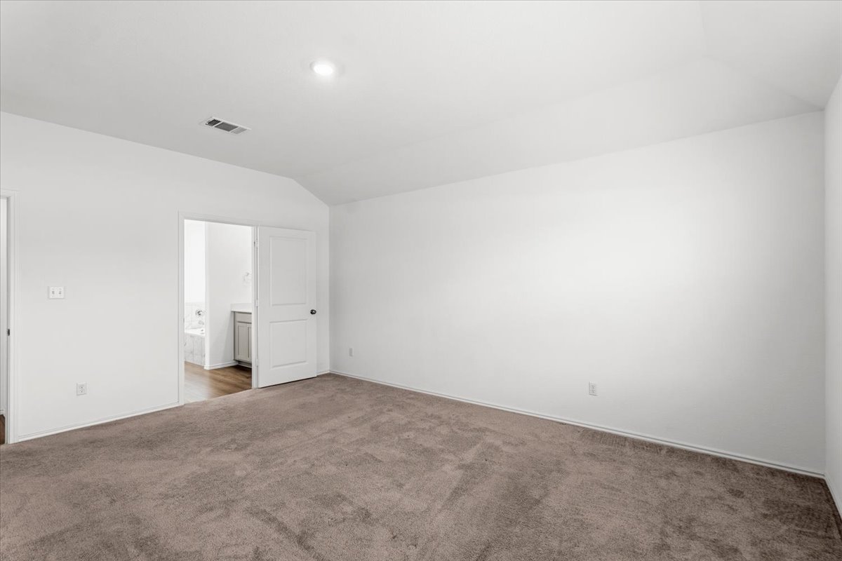 167 Jeffers Kyle, TX 78640 - Photo 23 of 40 Unfurnished bedroom with vaulted ceiling, carpet floors, and ensuite bath