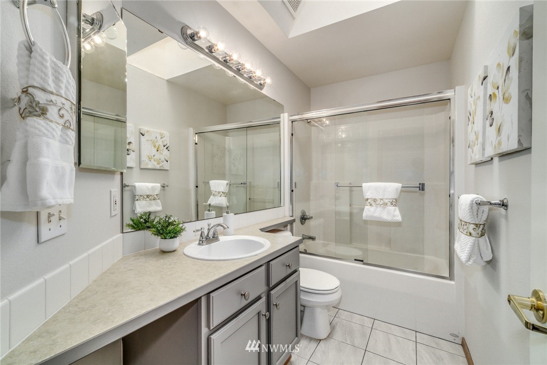 19212 1st Avenue West Bothell, WA 98012 - Photo 20 of 22 a bathroom with a granite countertop sink a toilet a shower and a mirror