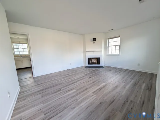 an empty room with wooden floor and a fireplace