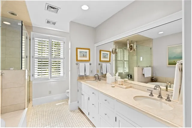 a bathroom with double vanity sinks a mirror and a bathtub