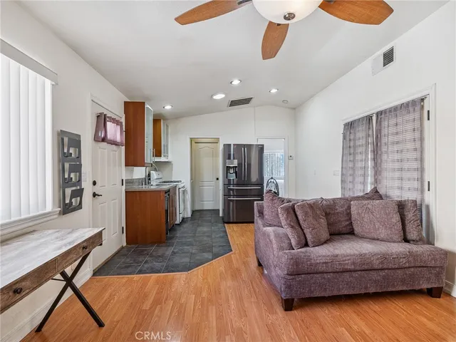 a living room with furniture a refrigerator and kitchen view