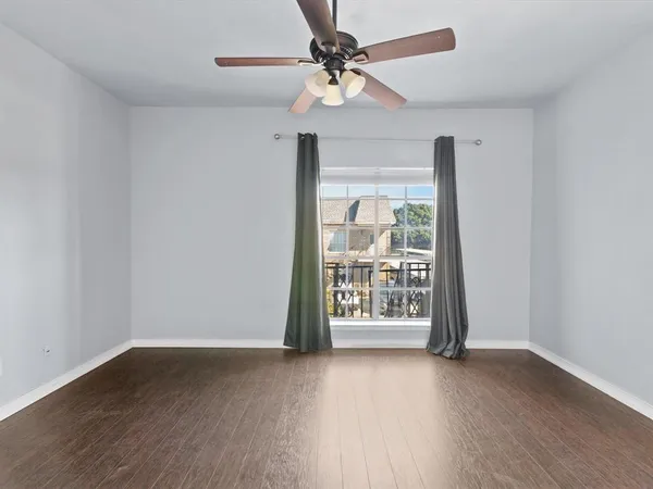 an empty room with wooden floor fan and windows