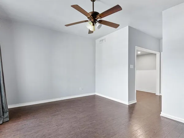 an empty room with wooden floor and a ceiling fan