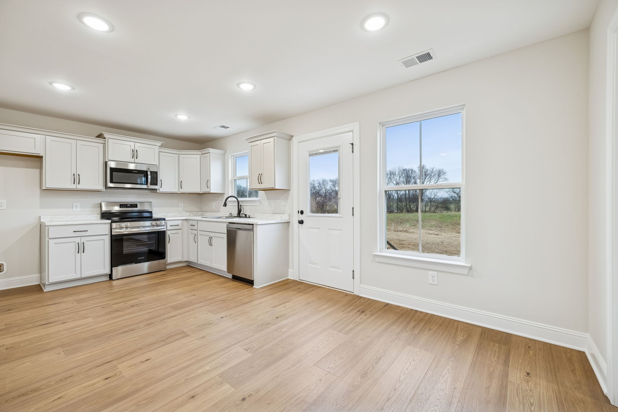 1035 Landing Lane Adams, TN 37010 - Photo 11 of 26 a kitchen with wooden floors white cabinets appliances and a window