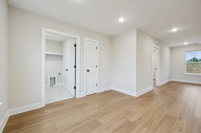 an empty room with wooden floor & cabinet and windows