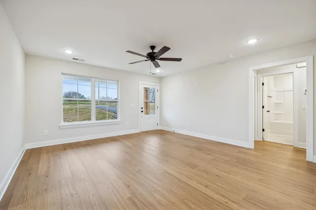 an empty room with wooden floor and windows