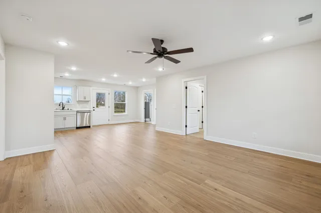 a view of empty room with wooden floor and kitchen view
