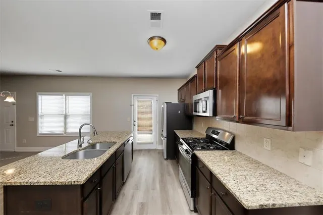 a kitchen with a granite countertop sink stove and refrigerator