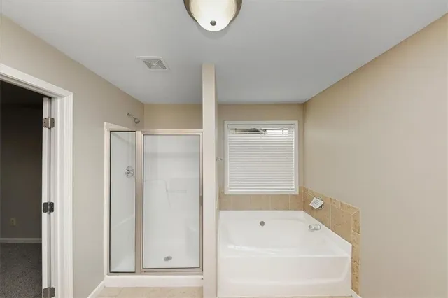 a bathroom with a tub a mirror and a shower