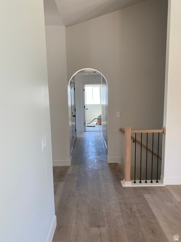 4676 West 75 North, Unit 401 West Point, UT 84015 - Photo 18 of 25 Arched doorway opening to a hallway featuring wood-finish flooring, crisp white baseboards, and a natural wood banister with black iron balusters