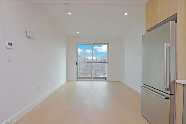 an empty room with kitchen view and a window