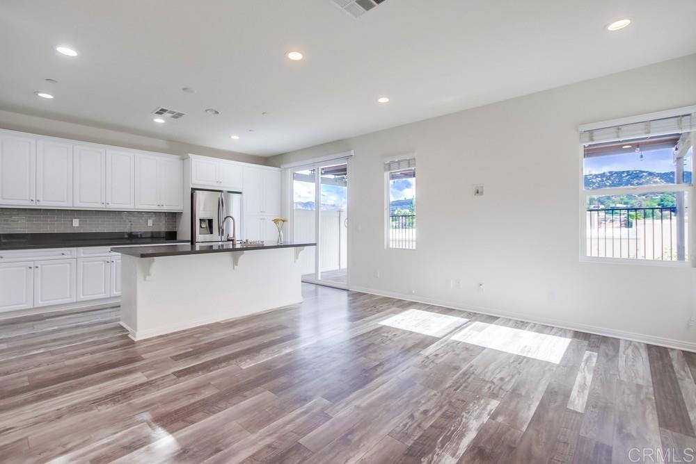 13109 Beacon View Lane El Cajon, CA 92021 - Photo 7 of 36 a large kitchen with stainless steel appliances granite countertop a stove a sink and white cabinets with wooden floor next to windows