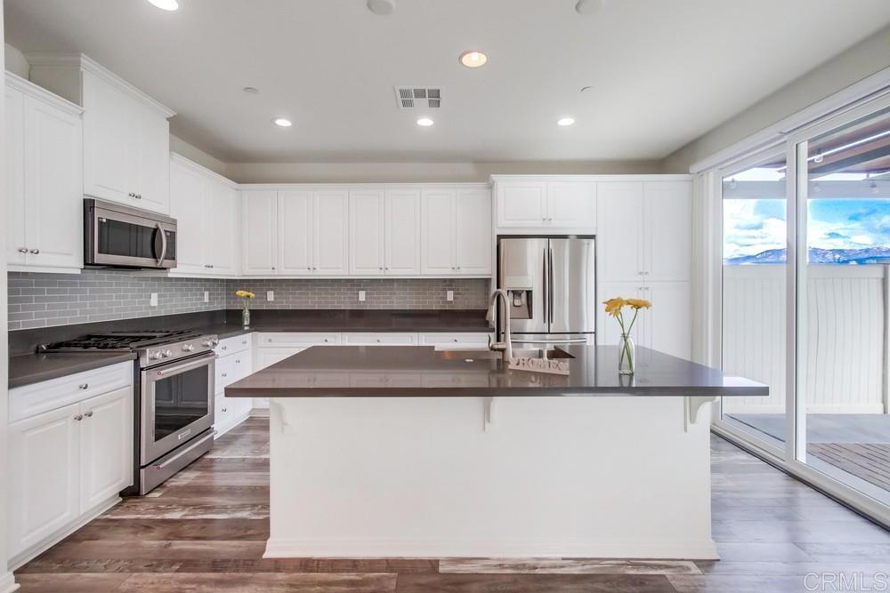 13109 Beacon View Lane El Cajon, CA 92021 - Photo 9 of 36 a kitchen with kitchen island granite countertop a stove top oven a sink a counter space and cabinets
