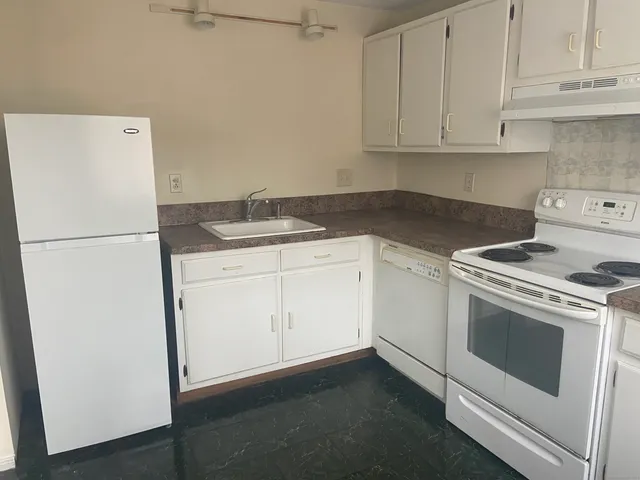 a kitchen with granite countertop white cabinets and white appliances