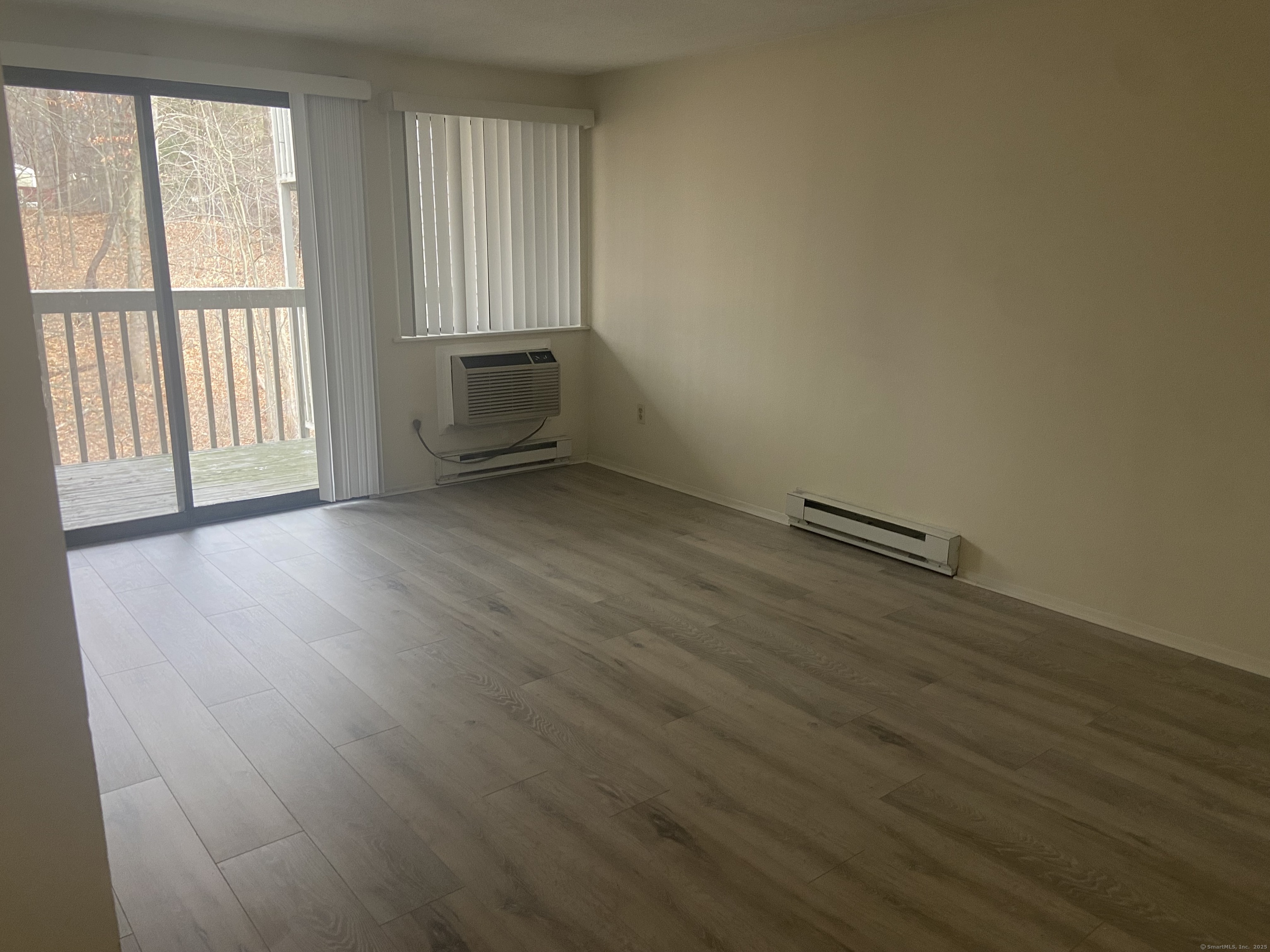 7 Padanaram Road, Unit J238 Danbury, CT 06811 - Photo 16 of 18 an empty room with wooden floor and windows