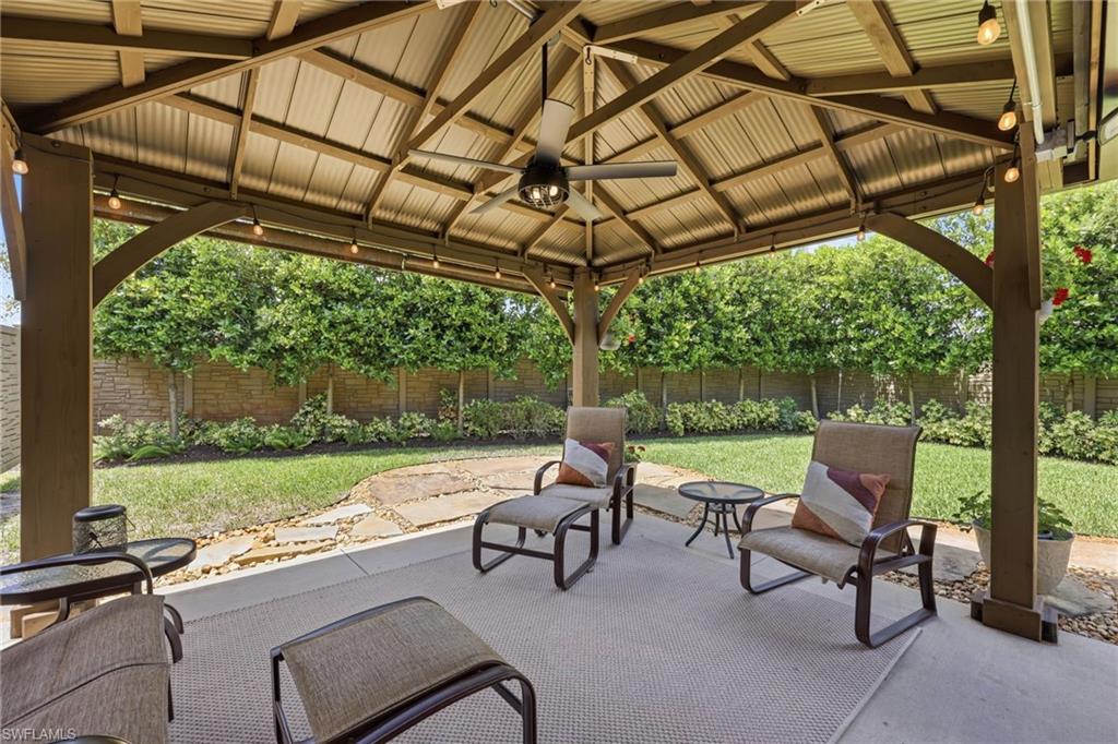5201 31st Place Southwest Naples, FL 34116 - Photo 21 of 24 a view of a patio with table and chairs under an umbrella with a large tree