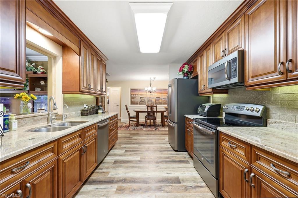 5201 31st Place Southwest Naples, FL 34116 - Photo 8 of 24 a large kitchen with stainless steel appliances granite countertop a stove a sink and a microwave