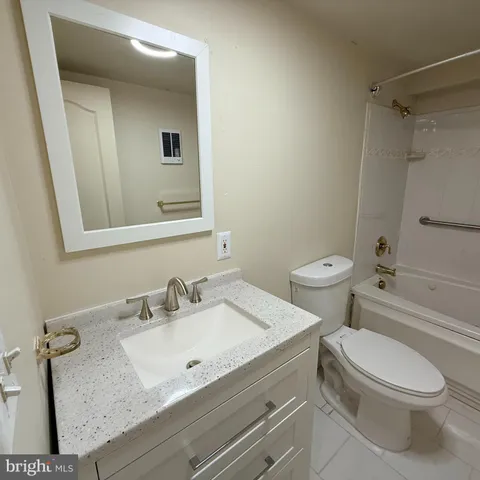 a bathroom with a granite countertop sink mirror vanity and toilet