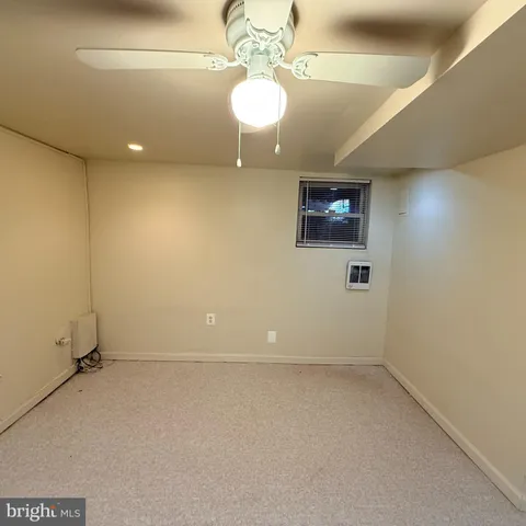 an empty room with a chandelier fan and wooden floor