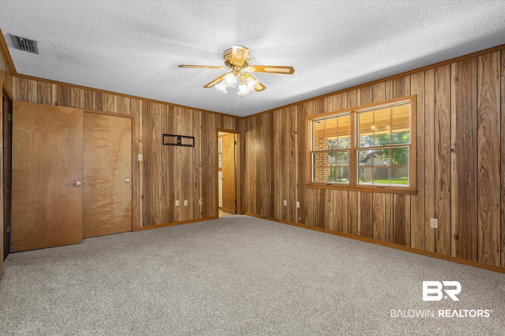 5503 Darring Street Satsuma, AL 36572 - Photo 14 of 31 Carpeted empty room featuring wood walls, ornamental molding, ceiling fan, and a textured ceiling