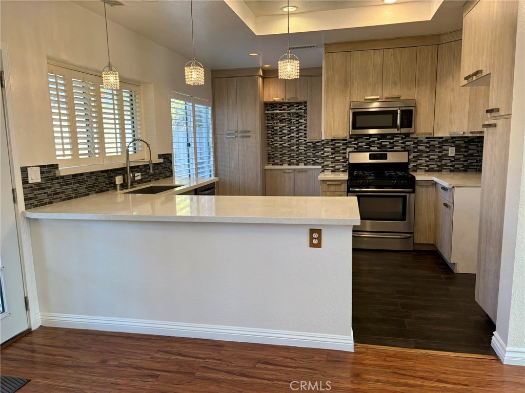7280 Comiso Way Rancho Cucamonga, CA 91701 - Photo 25 of 66 a kitchen with granite countertop a stove and a wooden floor