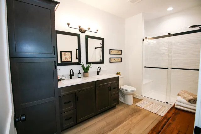 a bathroom with a double vanity sink toilet mirror and shower