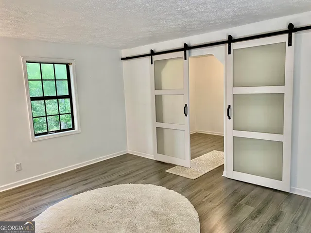 an empty room with wooden floor closet and windows