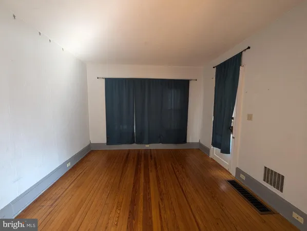 a view of an empty room with wooden floor and closet