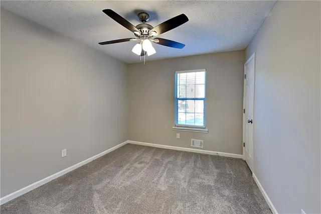 an empty room with windows and fan