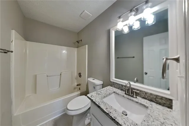 a bathroom with a granite countertop sink toilet a large mirror a shower and a bathtub
