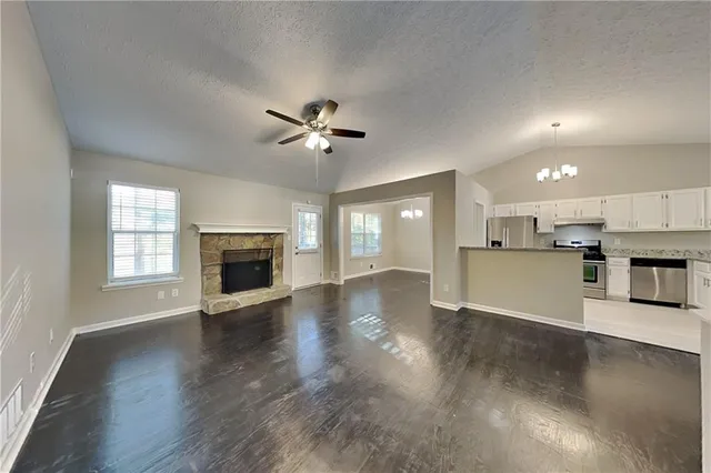 an empty room with wooden floor fireplace and windows