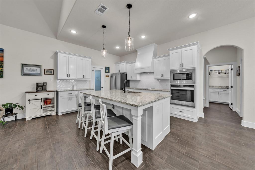 3000 Westfork Way Springtown, TX 76082 - Photo 12 of 35 a kitchen with stainless steel appliances kitchen island granite countertop a table chairs stove and white cabinets