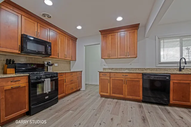 a kitchen with stainless steel appliances granite countertop wooden cabinets a stove top oven a sink and dishwasher